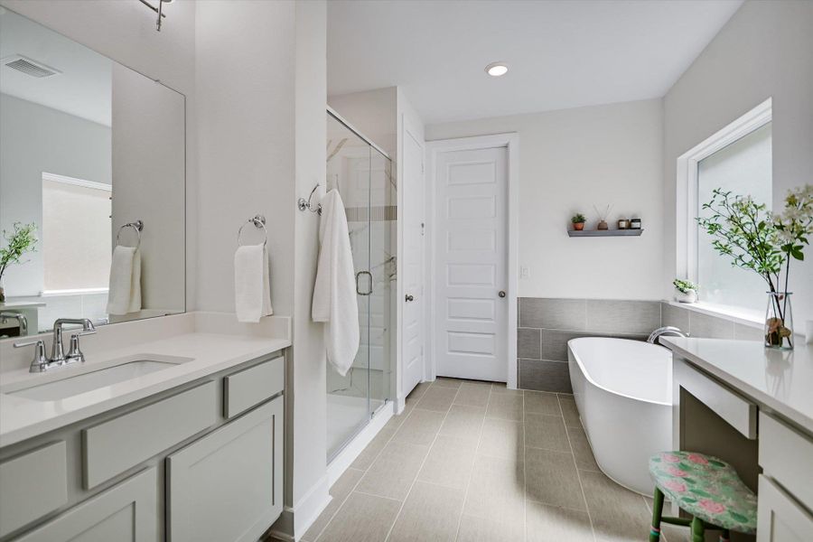 Main floor primary bath with soaking tub, separate shower and dual vanities