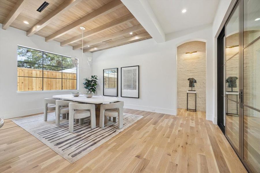 The dining room showcases a white oak ceiling, plaster chandelier and soaring window. A set of double doors lead you to the Pavilion.