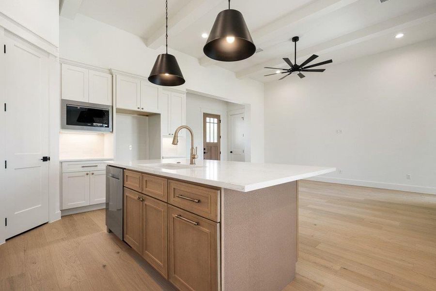 Modern kitchen with a large island featuring a white countertop and a stainless steel sink
