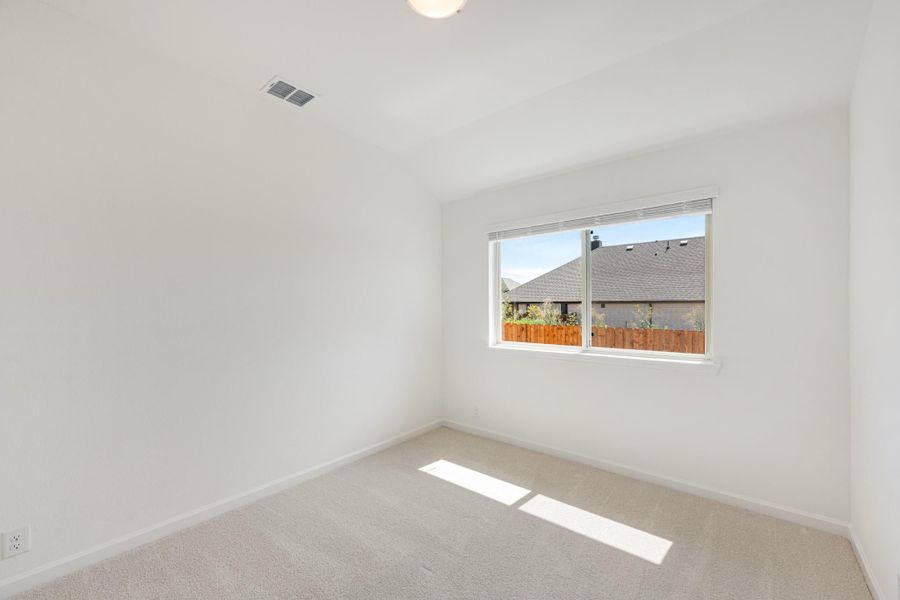 Empty bedroom with white walls, beige carpet, and a single window overlooking a neighboring home Empty bedroom with white walls, beige carpet, and a single window overlooking a neighboring home