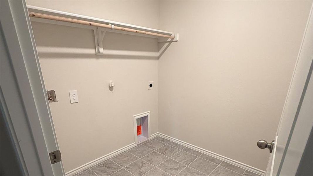Laundry area with hookup for a gas dryer, electric dryer hookup, and light tile patterned floors
