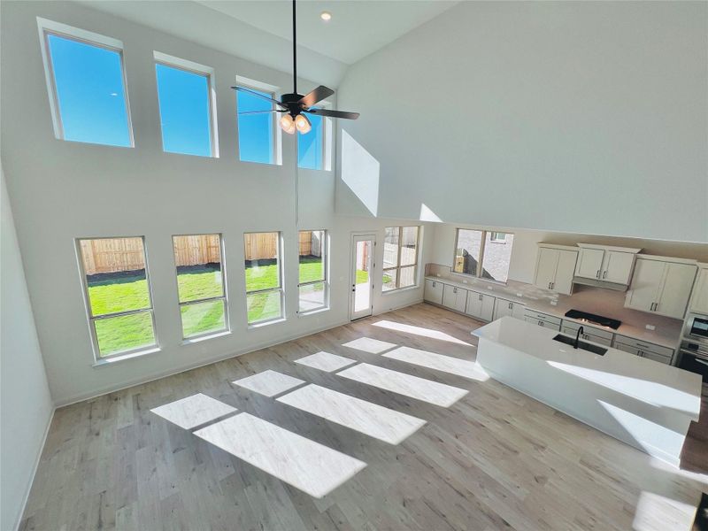 Unfurnished living room featuring a high ceiling, light wood-style flooring, recessed lighting, and ceiling fan