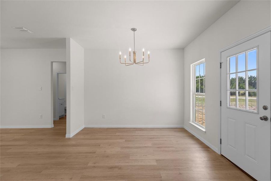 Unfurnished dining area featuring light wood-type flooring and a chandelier