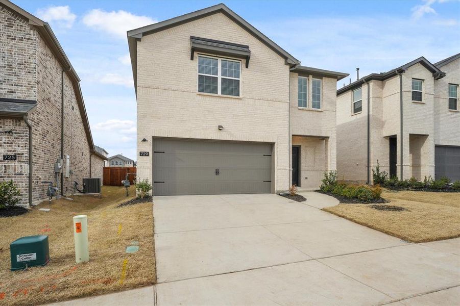 View of front of home with central AC unit and a garage