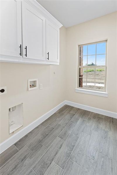 Washroom with cabinets, wood-type flooring, washer hookup, and hookup for an electric dryer