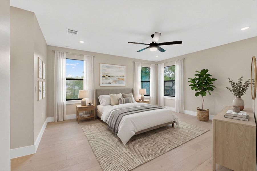 This tranquil bedroom features light wood flooring, several windows, and a ceiling fan for comfortable living.