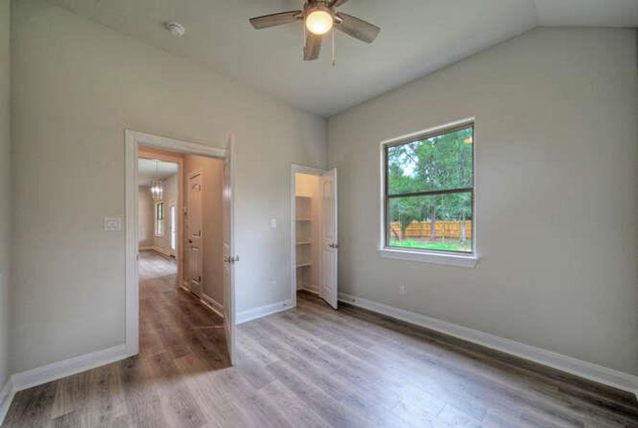 Unfurnished bedroom featuring wood finished floors, a ceiling fan, and vaulted ceiling