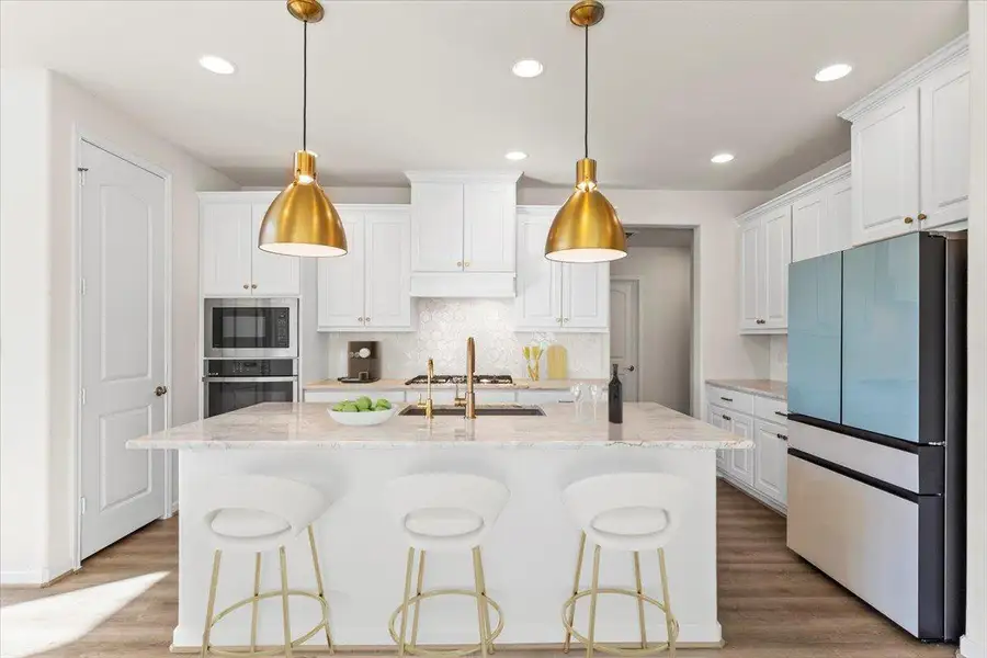 Kitchen featuring tasteful backsplash, stainless steel appliances, a kitchen bar, white cabinetry, and recessed lighting Kitchen featuring tasteful backsplash, stainless steel appliances, a kitchen bar, white cabinetry, and recessed lighting