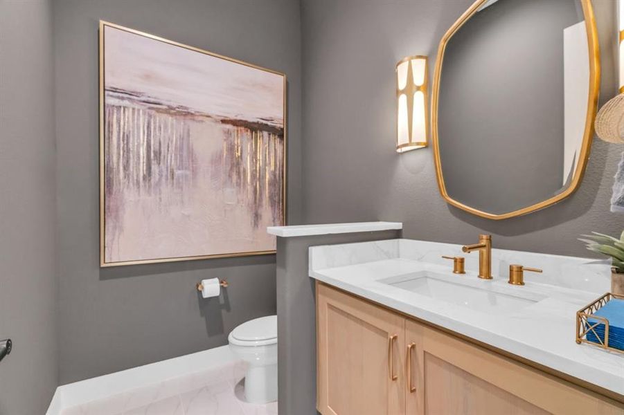 Powder room with beautiful wall sconces and a brass framed mirror.