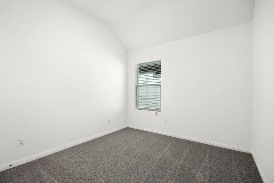 Empty room with dark carpet and lofted ceiling