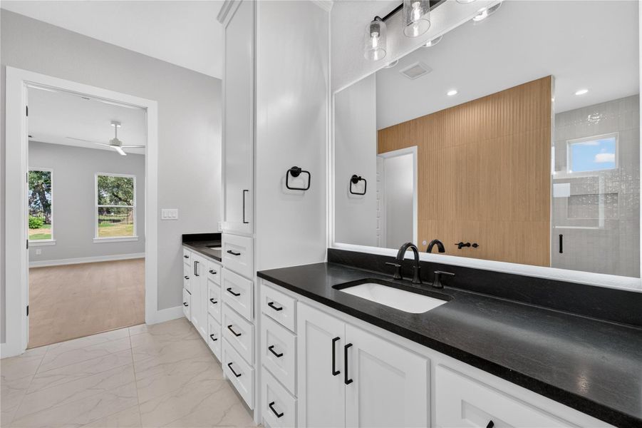 Gleaming stone countertops and pristine custom cabinetry elevate this modern bathroom design.