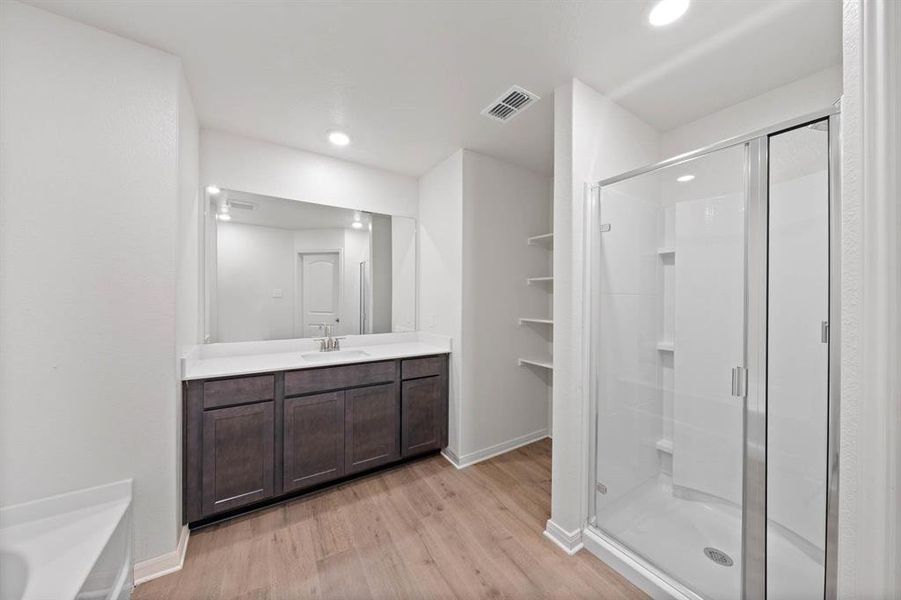 Bathroom featuring an enclosed shower, vanity, and wood-type flooring