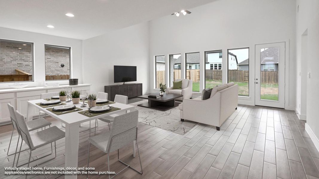 Living area with light wood finished floors, plenty of natural light, a high ceiling, and recessed lighting