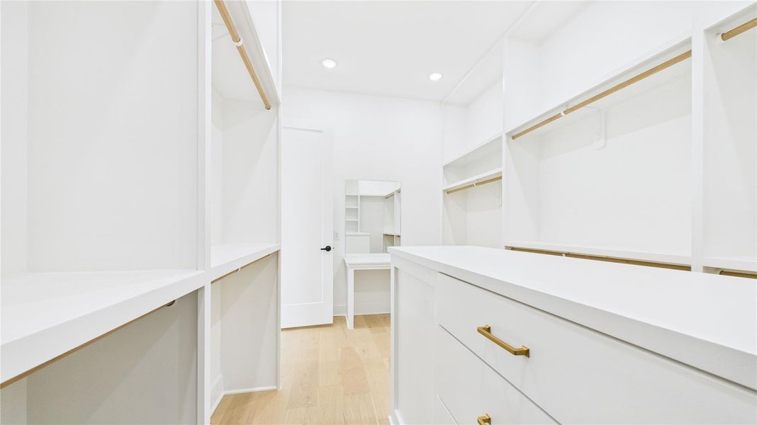 It has a bright, clean look with white cabinetry and gold hardware, complemented by light wood flooring.