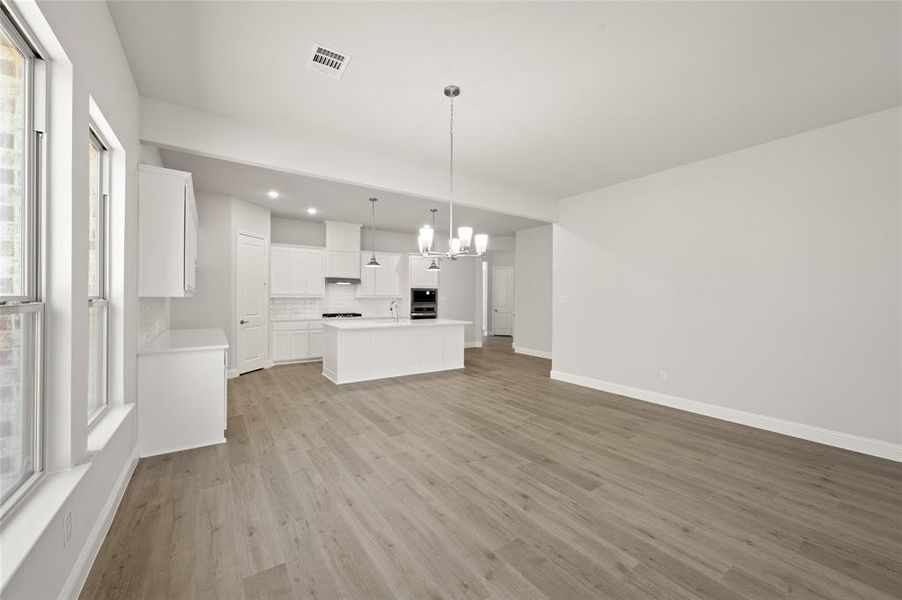 Kitchen with light countertops, pendant lighting, white cabinets, a chandelier, and open floor plan