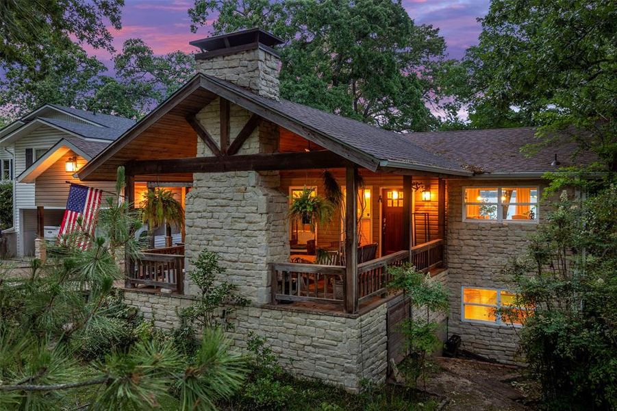 Stone exterior featuring a covered front porch with wood railings and exposed beam details