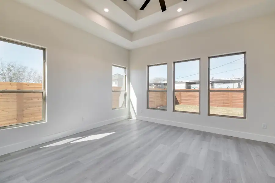 Unfurnished room featuring a raised ceiling, a ceiling fan, recessed lighting, light wood-style floors, and baseboards