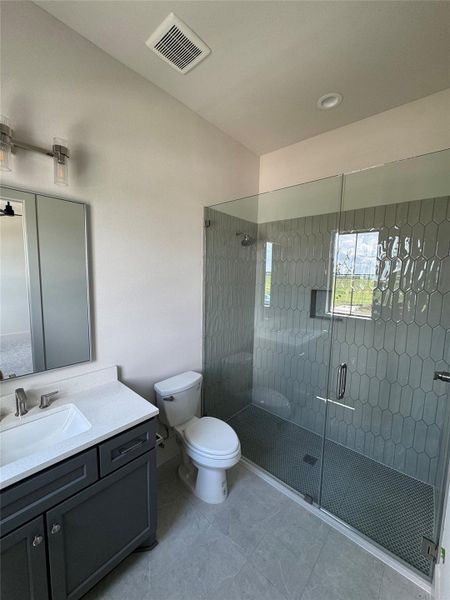 Bathroom with vanity, frameless glass shower, and designer tile finishes throughout.