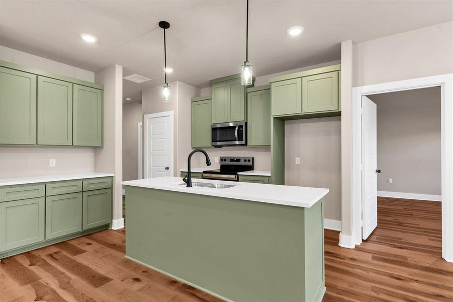 Kitchen featuring green cabinets, pendant lighting, stainless steel appliances, light wood-type flooring, and recessed lighting Kitchen featuring green cabinets, pendant lighting, stainless steel appliances, light wood-type flooring, and recessed lighting