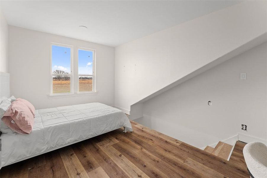 Spacious room featuring wood-finish flooring, white walls, and a pair of windows providing natural light Spacious room featuring wood-finish flooring, white walls, and a pair of windows providing natural light