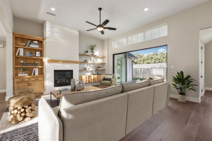 Living area with wood finished floors, a glass covered fireplace, ceiling fan, and recessed lighting