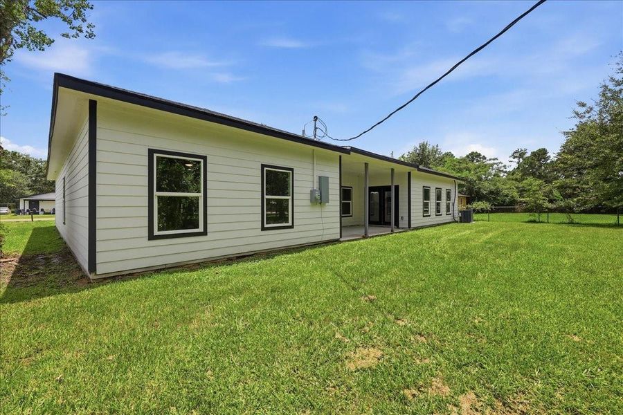 Rear exterior view showcasing the long covered back patio and expansive, open backyard. Rear exterior view showcasing the long covered back patio and expansive, open backyard.