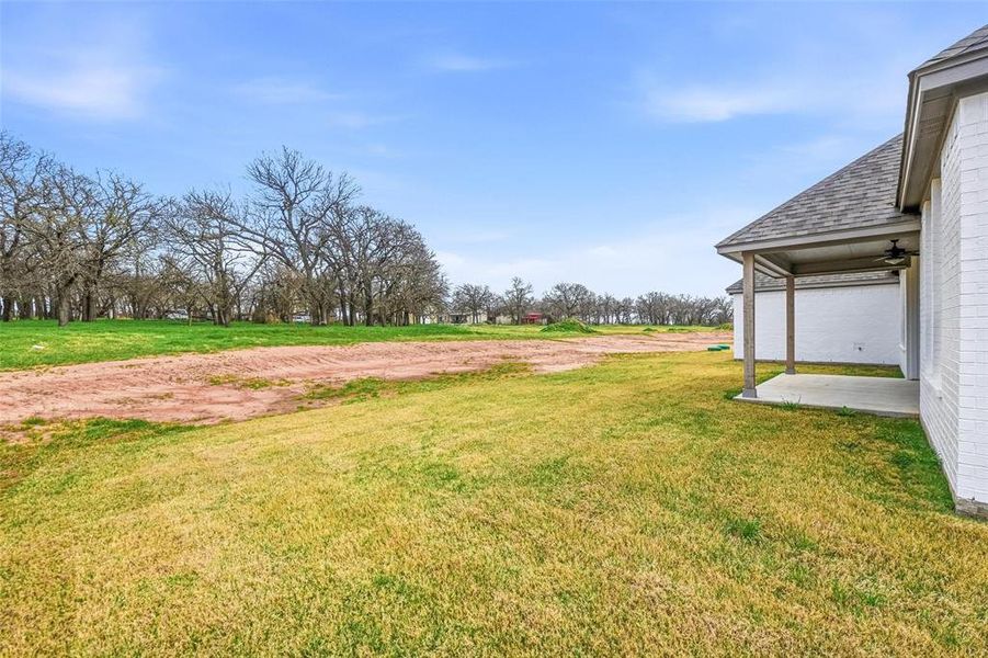 View of grassy yard with a patio area and ceiling fan