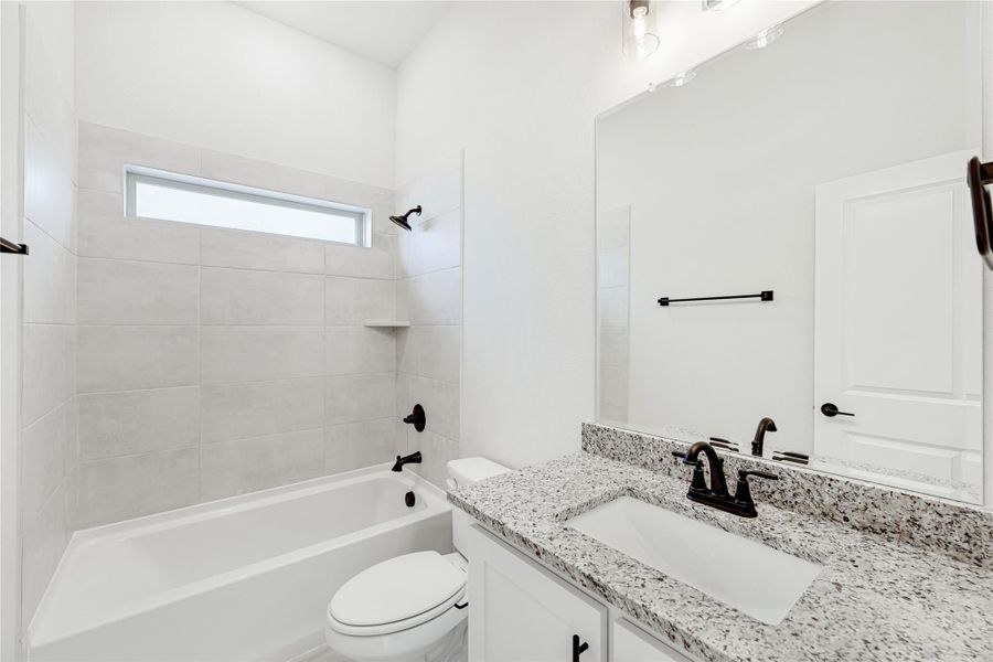 Bathroom with tiled tub-shower combo, granite vanity, white cabinets, and matte black fixtures