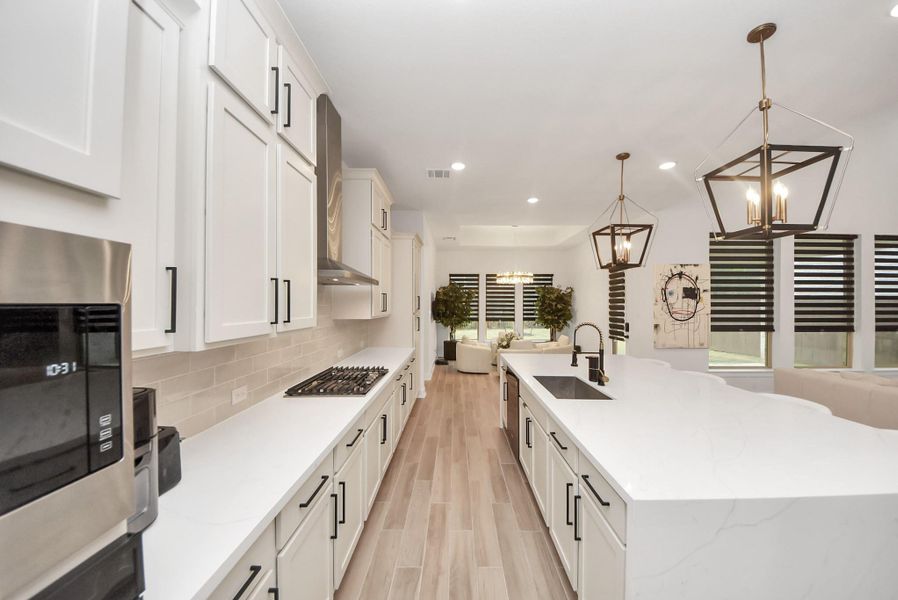 Elegant kitchen with quartz countertops, white cabinetry, black hardware, gas cooktop, built-in microwave and oven, plus abundant counter and cabinet space.