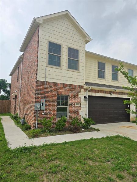 View of front facade featuring a garage, concrete driveway, and brick siding