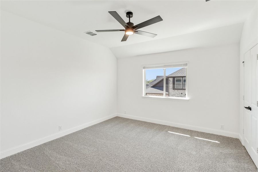 Empty bedroom with vaulted ceiling, ceiling fan, gray carpet, and single window Empty bedroom with vaulted ceiling, ceiling fan, gray carpet, and single window