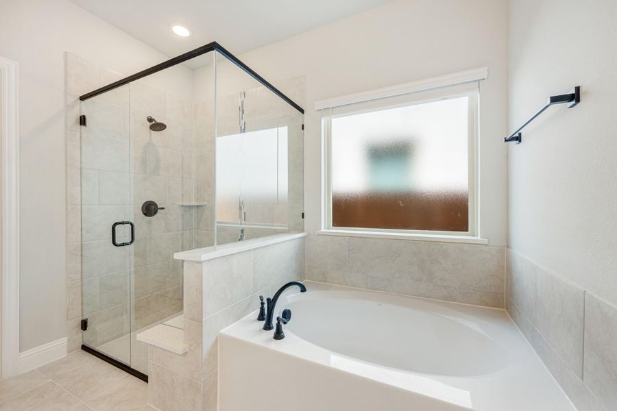 Bathroom with soaking tub, glass-enclosed shower, tile walls, and matte black fixtures