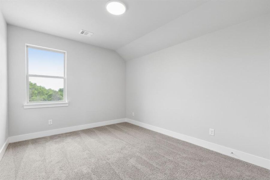 Carpeted empty room featuring baseboards and vaulted ceiling Carpeted empty room featuring baseboards and vaulted ceiling