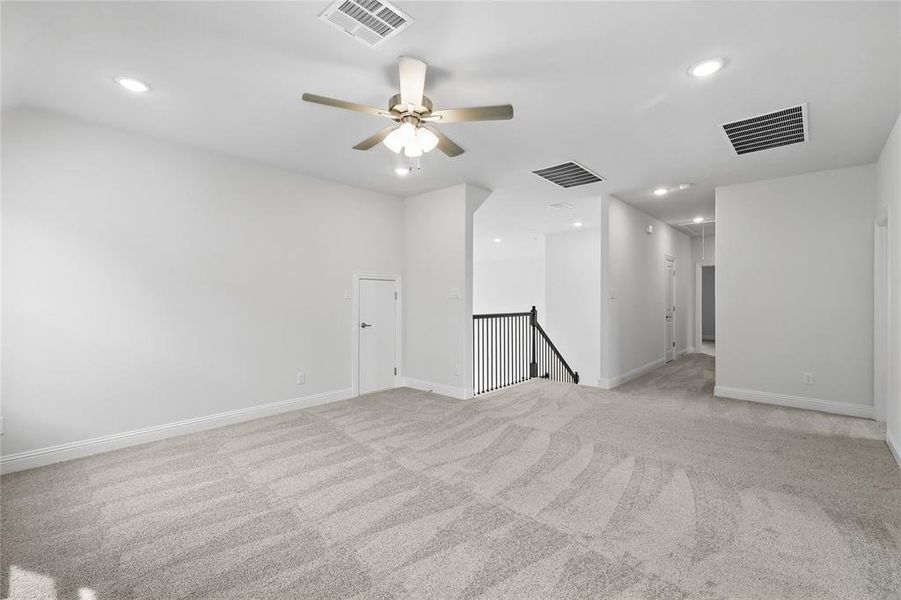 Empty room featuring light carpet, baseboards, visible vents, and recessed lighting