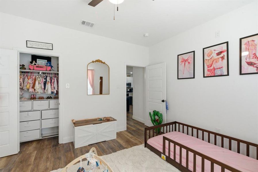 Bedroom featuring dark wood-style flooring, ceiling fan, and a spacious closet Bedroom featuring dark wood-style flooring, ceiling fan, and a spacious closet