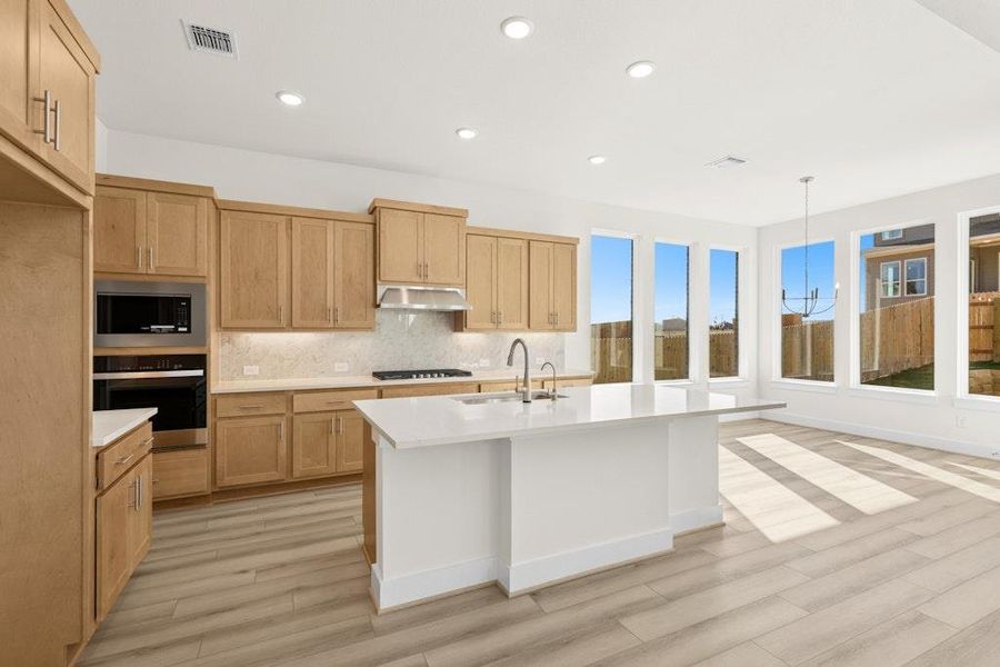 Kitchen with decorative backsplash, decorative light fixtures, recessed lighting, appliances with stainless steel finishes, and a center island with sink Kitchen with decorative backsplash, decorative light fixtures, recessed lighting, appliances with stainless steel finishes, and a center island with sink