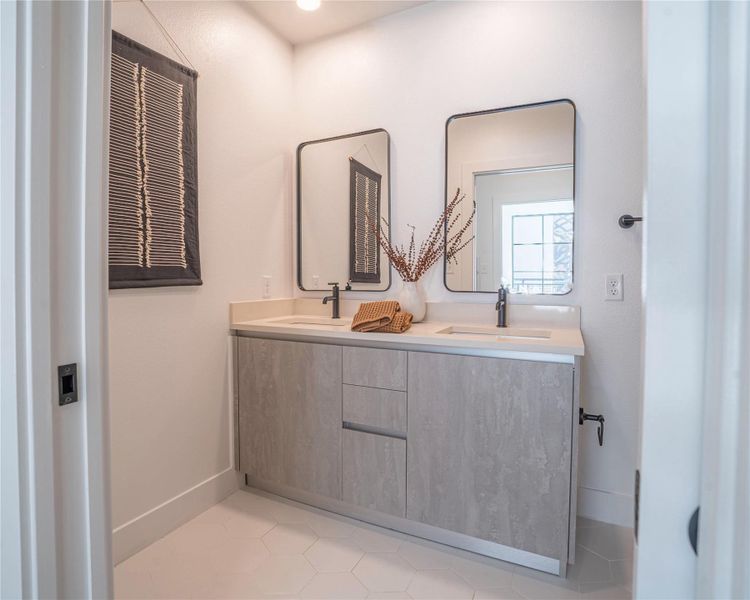 Full bathroom featuring double vanity and light tile patterned floors.Photos shown are of a model residence and are representative in nature. Actual residence may differ in layout, finishes, and views.