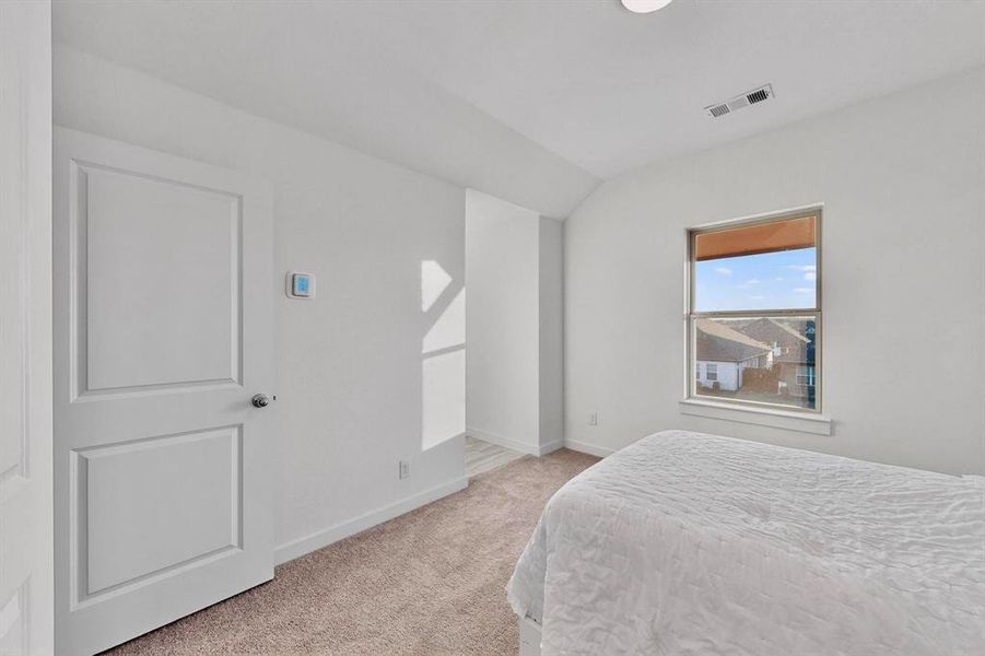 Bedroom featuring light colored carpet and vaulted ceiling Bedroom featuring light colored carpet and vaulted ceiling