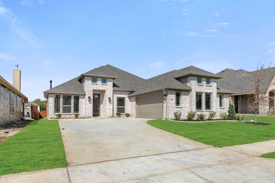 Single-story brick home with two-car garage, concrete driveway, and green front lawn