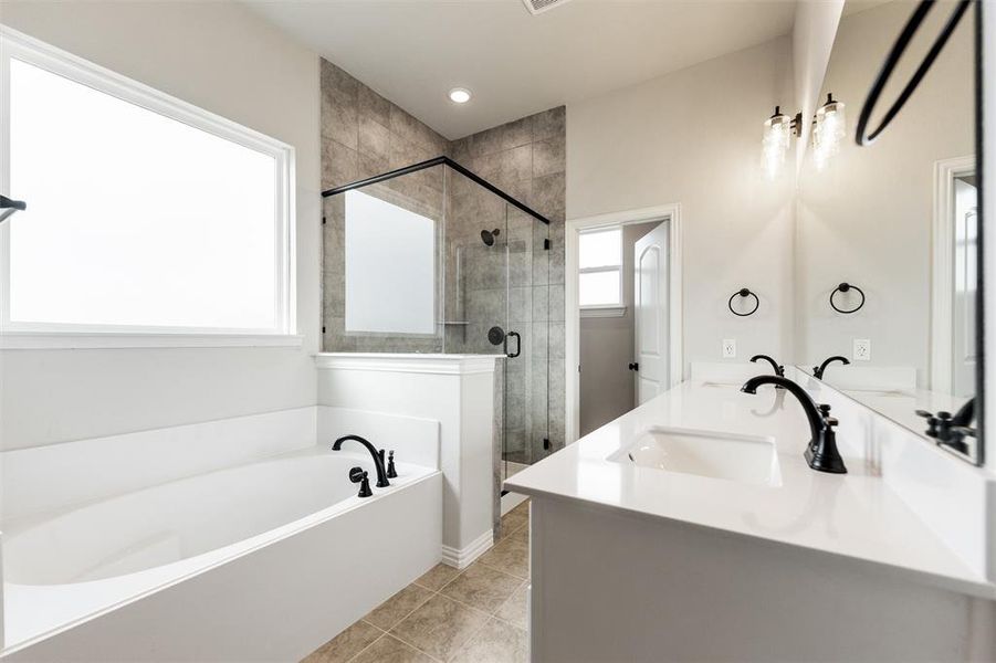 Bathroom featuring a garden tub, double vanity, a stall shower, and light tile patterned floors Bathroom featuring a garden tub, double vanity, a stall shower, and light tile patterned floors