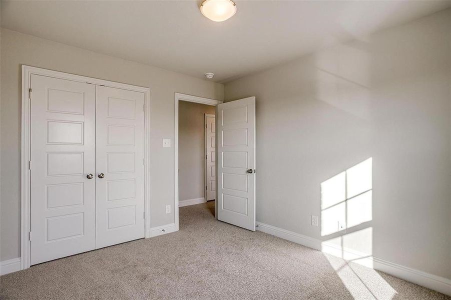 Unfurnished bedroom with light colored carpet and a closet Unfurnished bedroom with light colored carpet and a closet