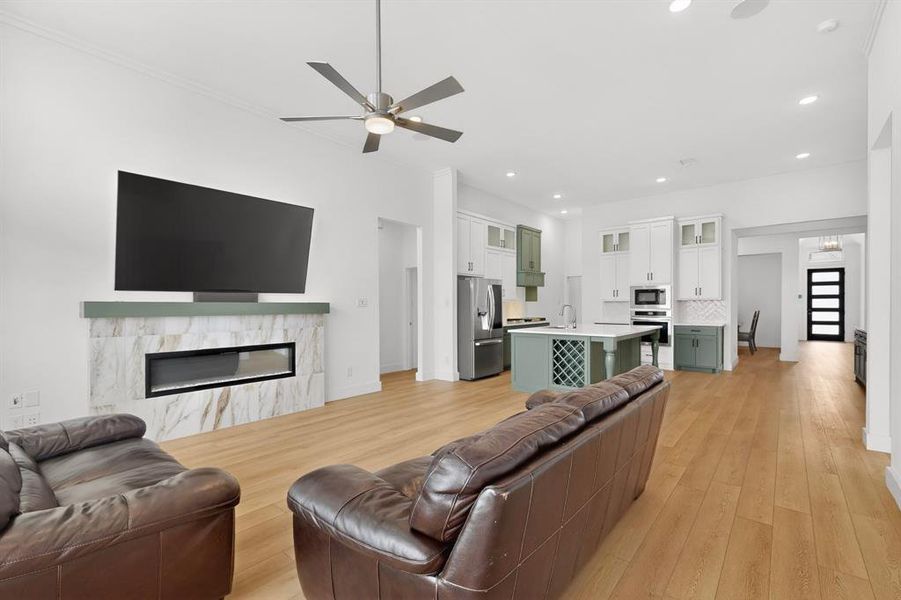 Spacious open-concept living area featuring wood-finish flooring, recessed lighting, and a ceiling fan Spacious open-concept living area featuring wood-finish flooring, recessed lighting, and a ceiling fan