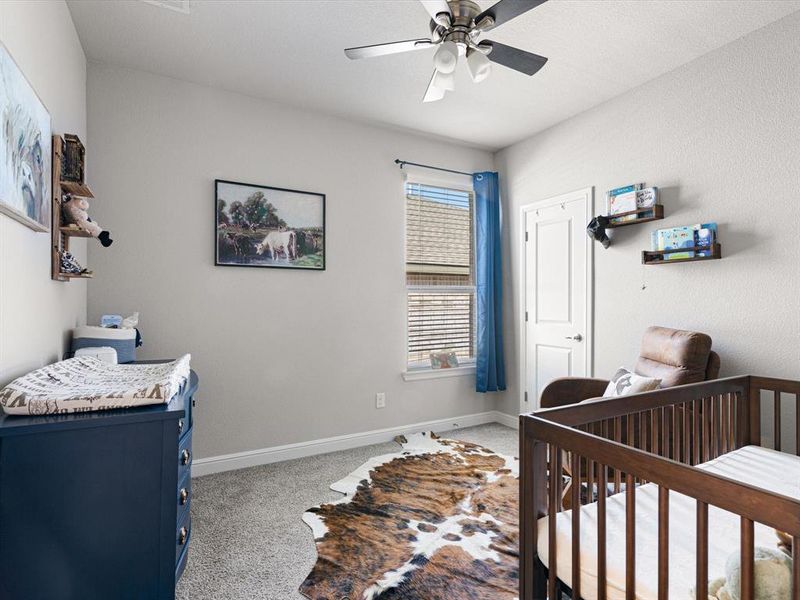 Bedroom with ceiling fan, carpet, and a crib