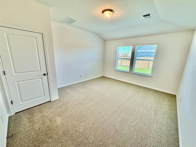 Empty room with carpet flooring, vaulted ceiling, and a textured ceiling