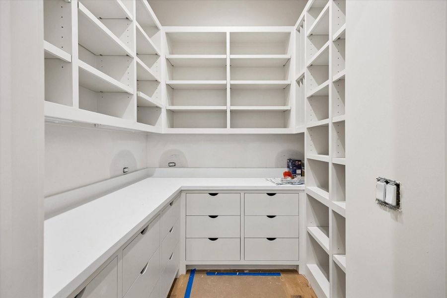 The chef’s pantry offers abundant cabinetry, along with dedicated prep space and ample appliance storage.