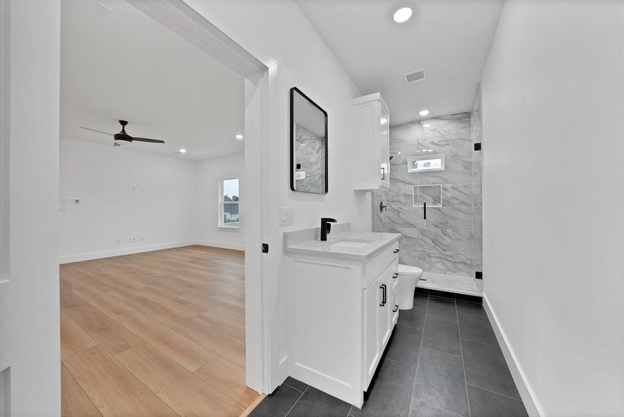Modern bathroom featuring a white vanity with black hardware, a rectangular mirror, and a tiled shower with a niche