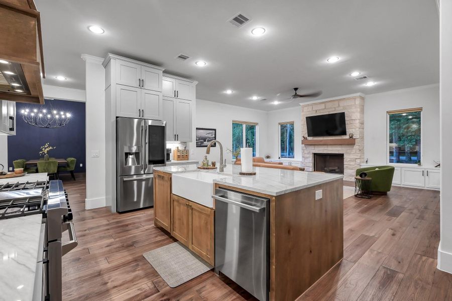 The kitchen showcases a modern open-concept kitchen and living area. It features a large island with a farmhouse sink, stainless steel appliances, and soft close cabinetry.