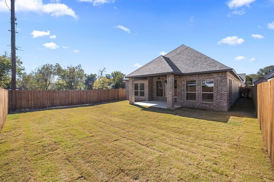 Spacious backyard with a wood privacy fence, sodded lawn, and a covered concrete patio Spacious backyard with a wood privacy fence, sodded lawn, and a covered concrete patio