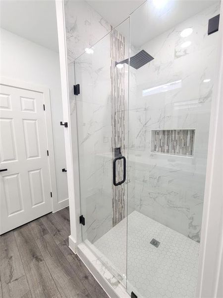 Full bathroom featuring a marble finish shower and wood finished floors Full bathroom featuring a marble finish shower and wood finished floors