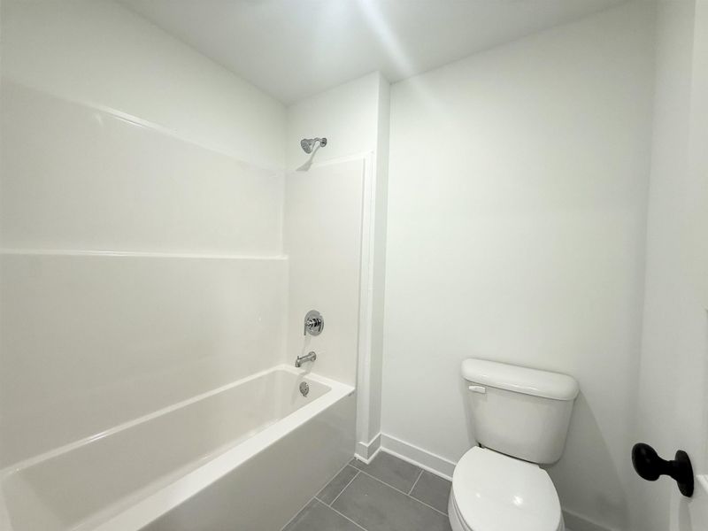 Bathroom with dark tile patterned floors and shower / tub combination